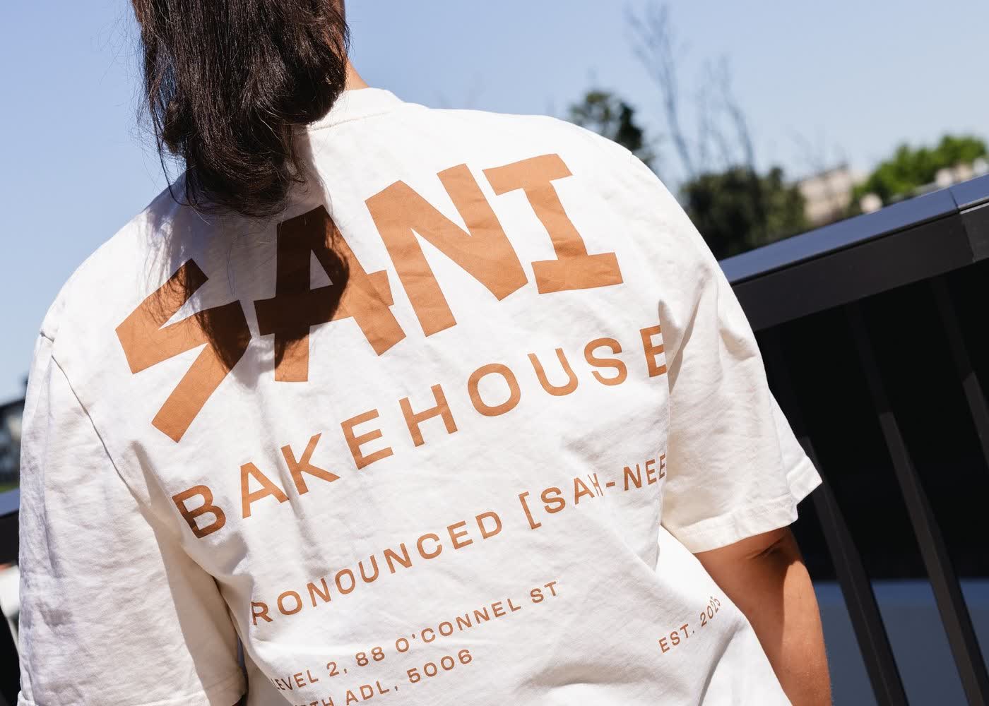 Two people holding SANI matcha lattes outside the bakehouse.